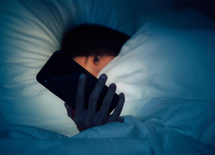 Girl Scrolling in her phone before bed