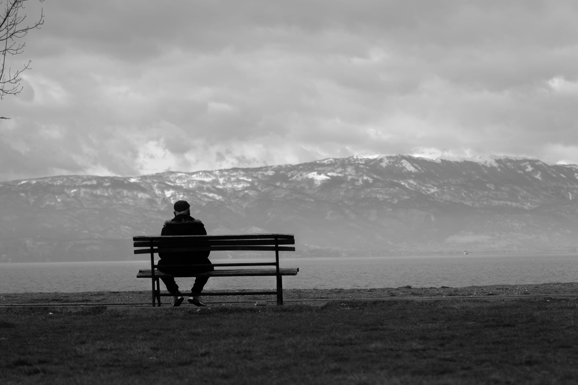 Black-and-white photo of a man sitting alone in thought — reflective, not dramatic