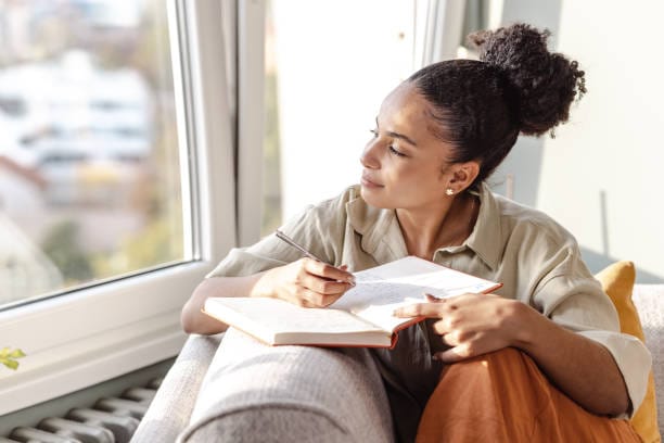 Black Woman Journaling Sitting Near Window